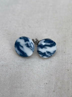 Clous d’oreilles en porcelaine, disques marbrés bleu et blanc, avec tige métallique.