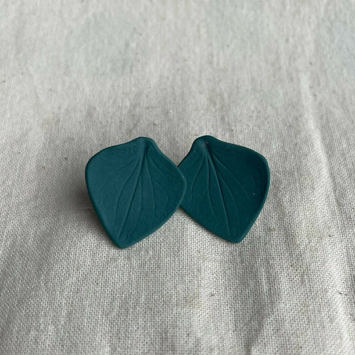 Boucles d’oreilles en porcelaine, deux pastilles en forme de feuilles vert foncé.