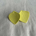 Boucles d’oreilles en porcelaine, deux pastilles en forme de feuilles jaune.