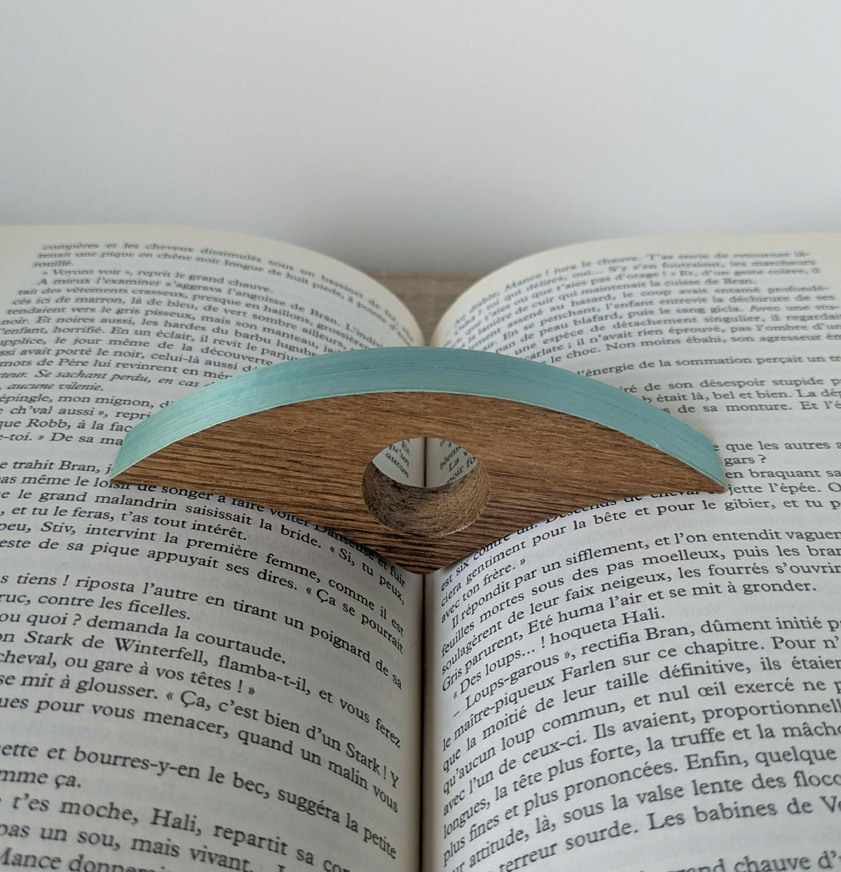 Bague de lecture en bois turquoise, sur les pages d’un livre imprimé
