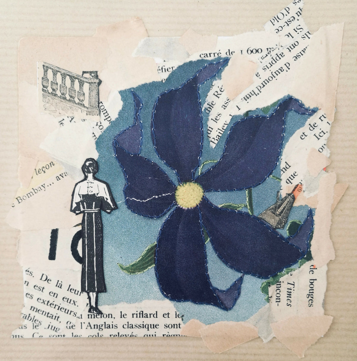 Collage papier avec grande fleur bleue en relief, pétales découpés et fragments de texte