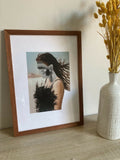 Collage encadré : cadre en bois brun, portrait de femme à robe noire en plumes