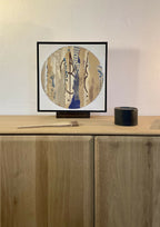 Collage sur bois ARGILE dans cadre noir, composition circulaire abstraite bleu et beige.