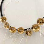 Bracelet à cordon noir et médaillons dorés, vue rapprochée