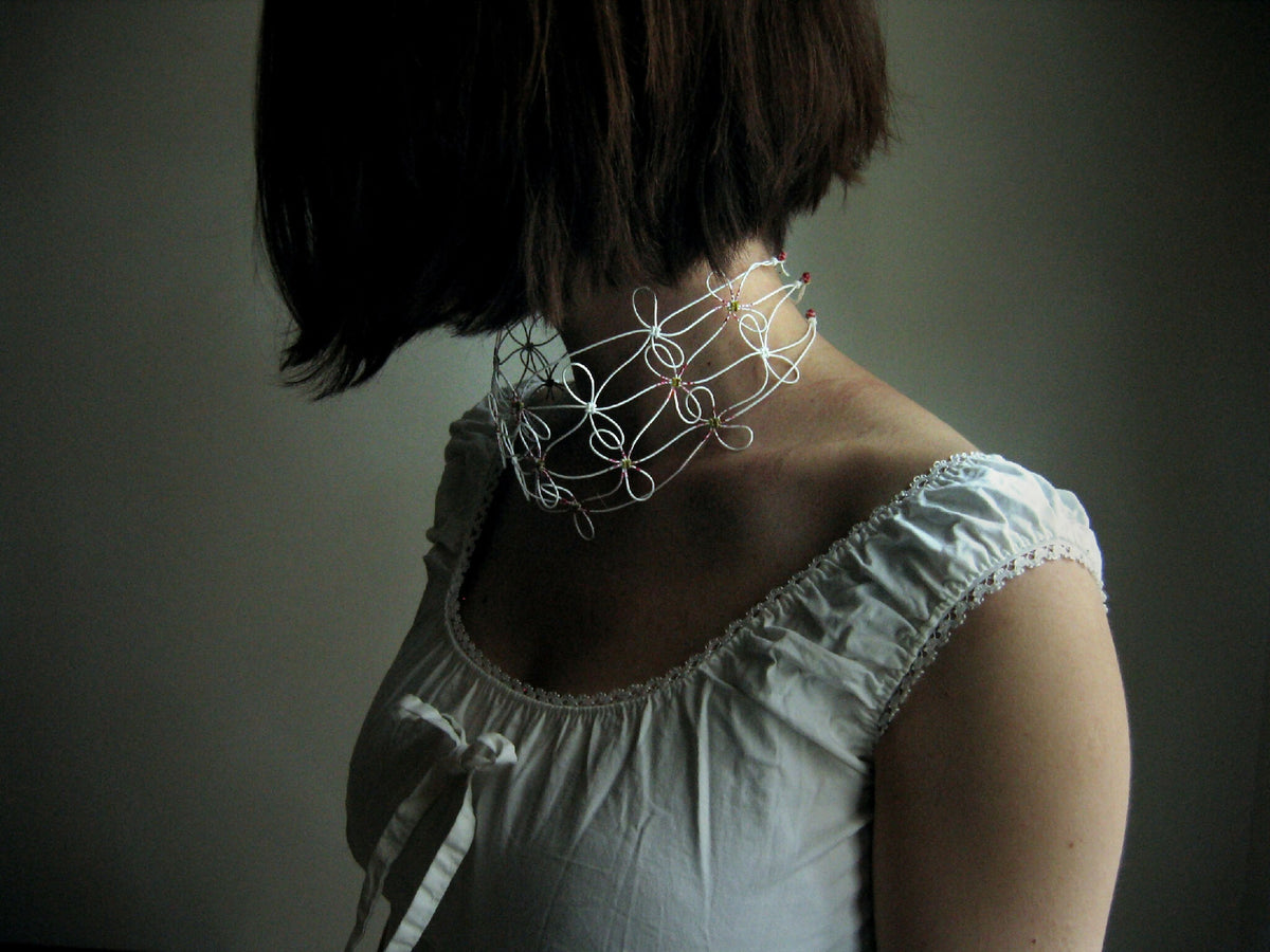 Collier en fil blanc fin, motifs torsadés avec perles autour du cou