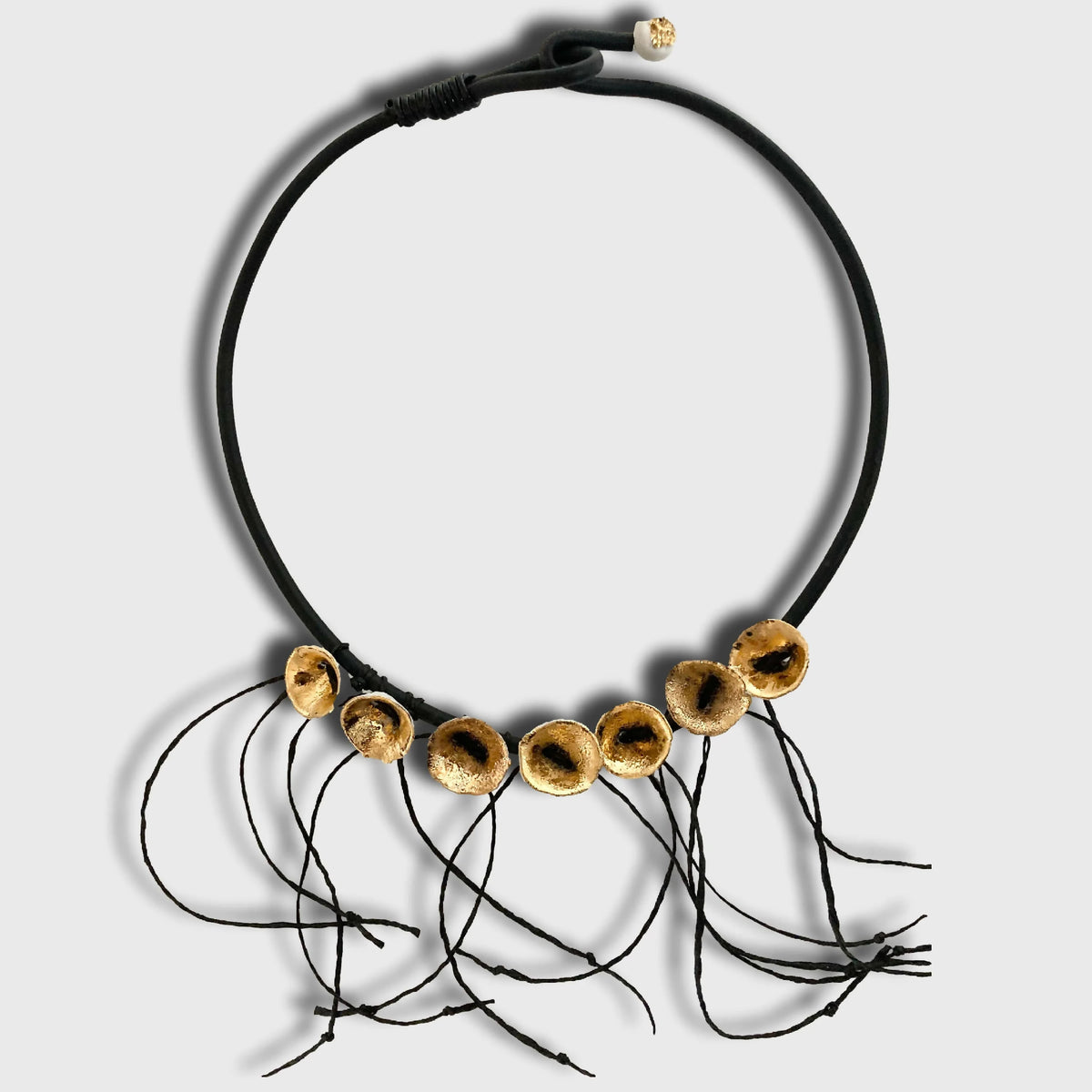 Collier noir en cordon avec disques dorés percés et petits fils noirs pendants