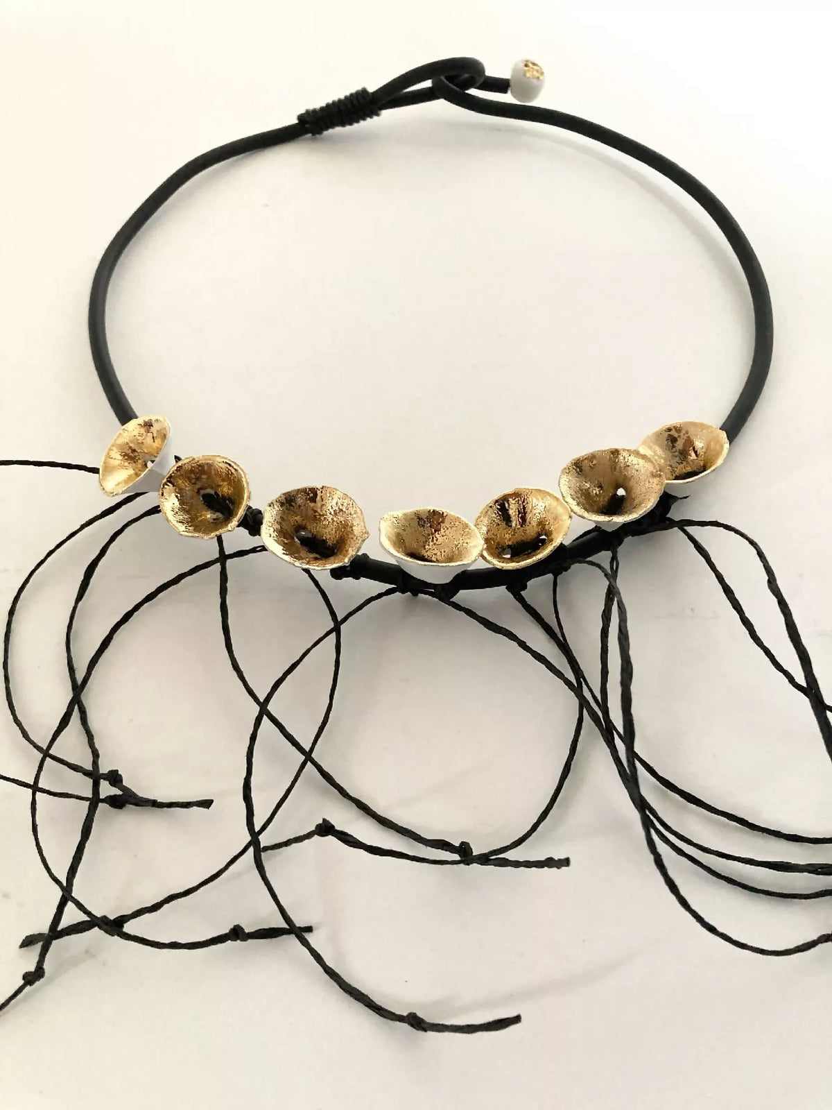 Collier en cordon noir avec plusieurs disques dorés et fils noirs décoratifs