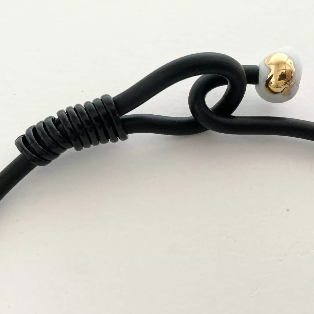 Collier : fermeture avec perle dorée sur cordon noir torsadé