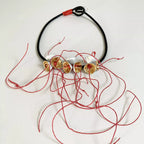 Collier à cordon noir avec fleurs dorées et fils rouges décoratifs