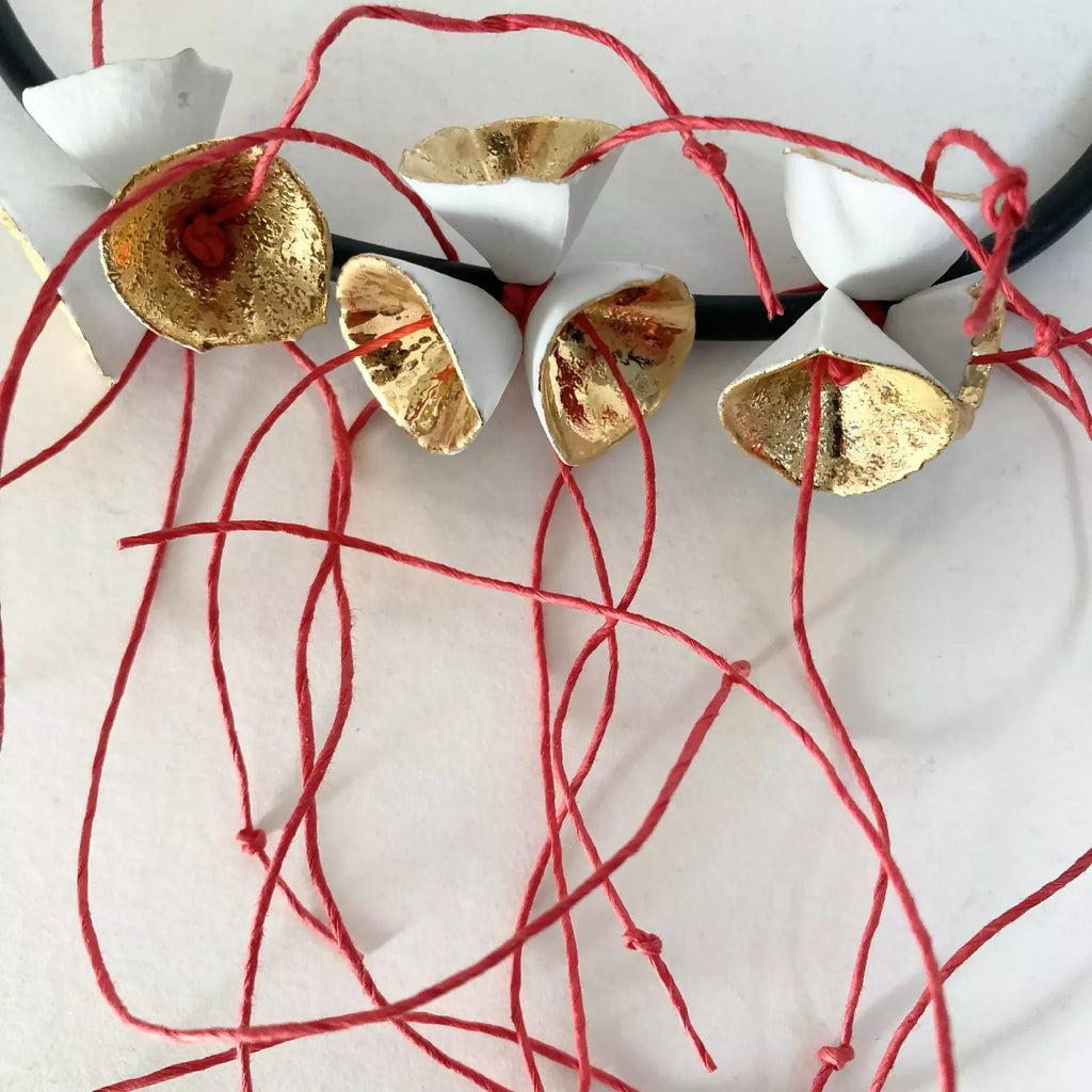 Collier fleuri : pendentifs dorés sur cordon noir, fils rouges noués