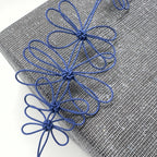 Collier de fleurs de prunier bleu : gros plan sur fleurs en fil et pétales bouclés.