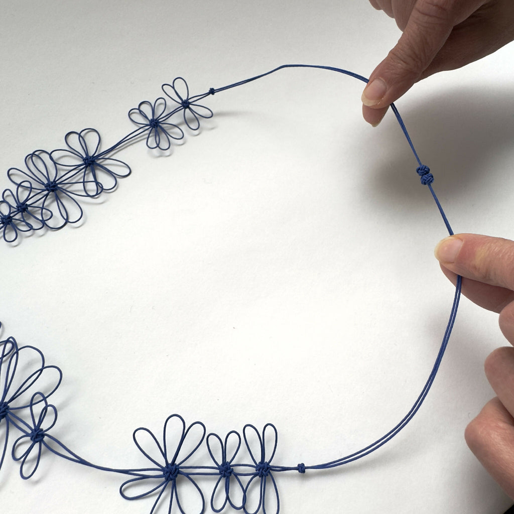 Collier de fleurs de prunier bleu : ajustement avec nœuds et boucle au col.