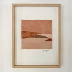 Collage textile abstrait en cadre bois clair, formes horizon, tons terre cuite et beige.