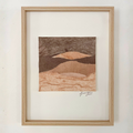 Collage textile encadré en bois clair, paysage abstrait de collines aux tons bruns et beiges.