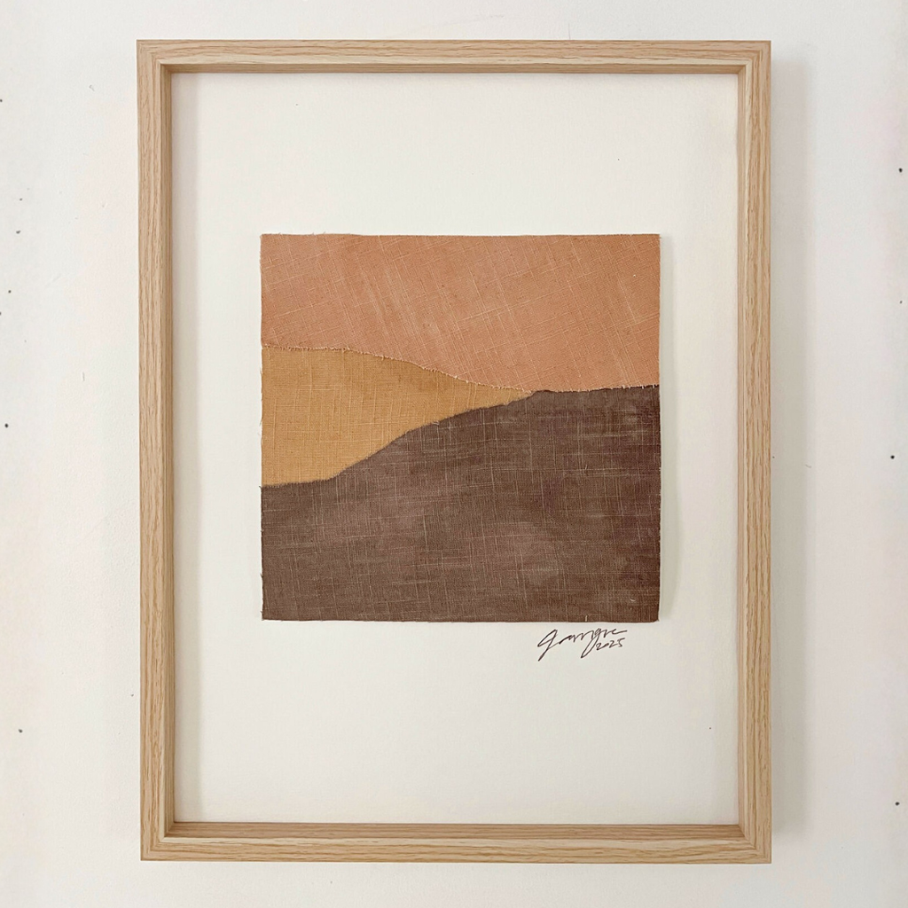 Collage textile abstrait carré avec signature, collines en terre cuite et brun foncé, cadre bois.