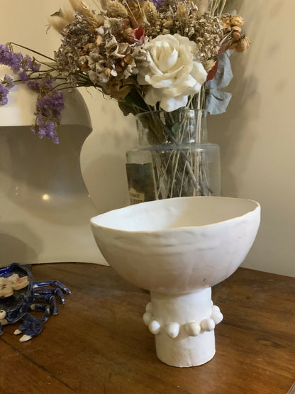Coupelle en céramique blanche sur table, base ornée de pastilles