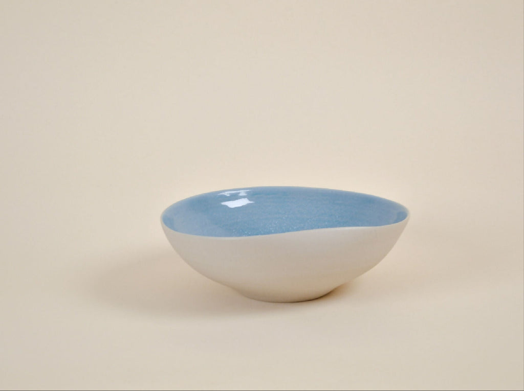 Coupe en céramique blanche à intérieur bleu, forme arrondie, bord évasé.