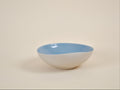Coupe en céramique blanche à intérieur bleu, forme arrondie, bord évasé.