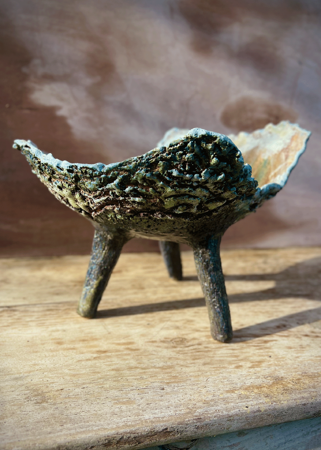 Coupe ou jardinière tripode en céramique patinée bleu foncé, bord ondulé, trois pieds visibles.