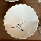 Coupelle en porcelaine blanche, bord festonné, oiseau noir posé, décor artisanal peint