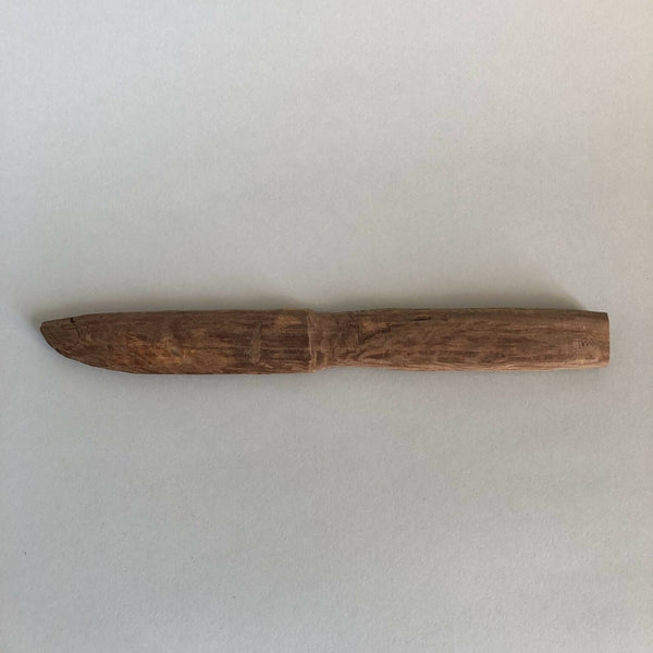 Couteau en bois taillé, lame effilée et manche intégré, brun, vue de profil.