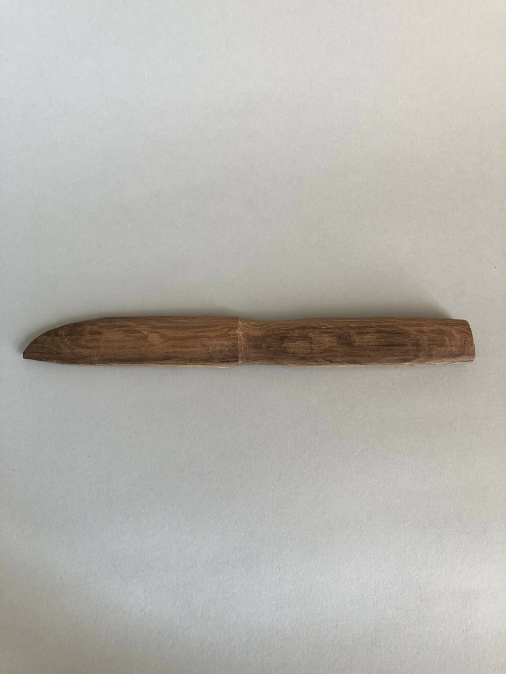 Couteau en bois taillé, lame rectiligne et manche intégré, brun, vue horizontale.