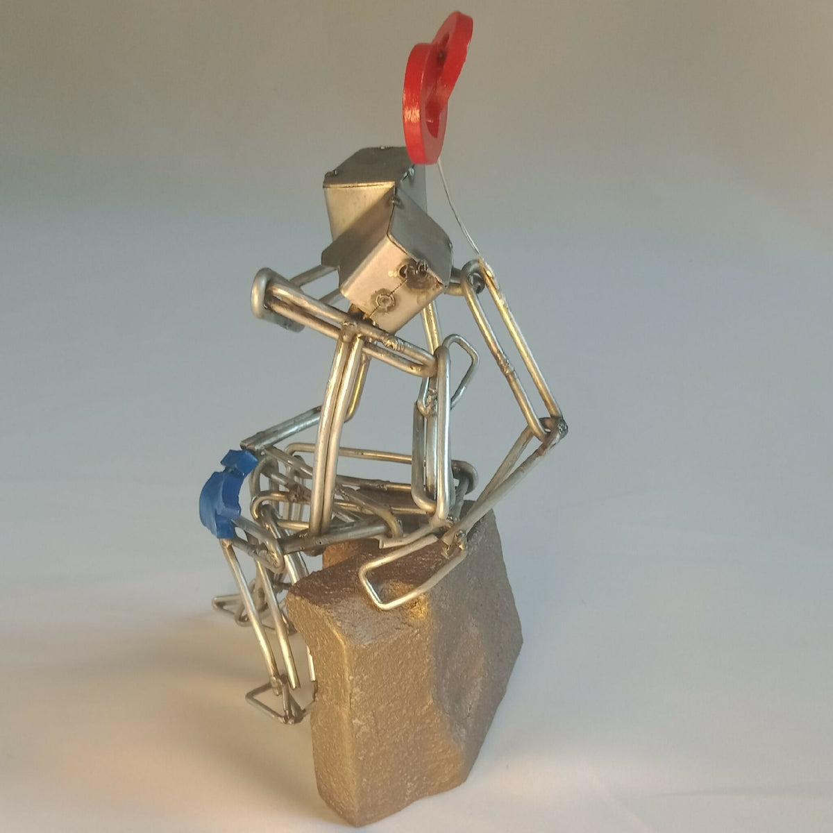 Sculpture en fils d’acier, couple sur socle doré, cœur rouge et assise bleue visibles