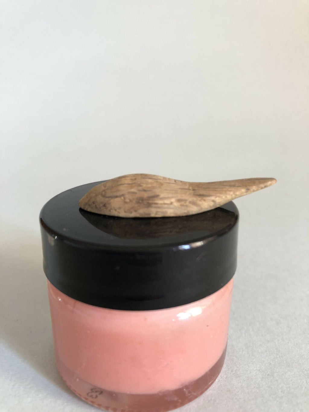 Cuillère à cosmétiques en bois sur pot rose à couvercle noir