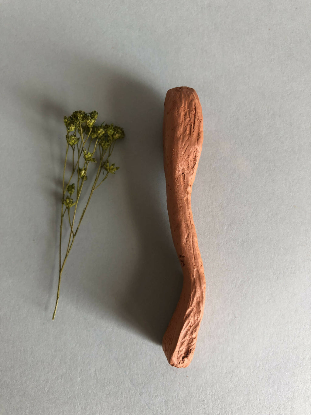 Cuillère à thé en bois cuivré, manche étroit et extrémité effilée.