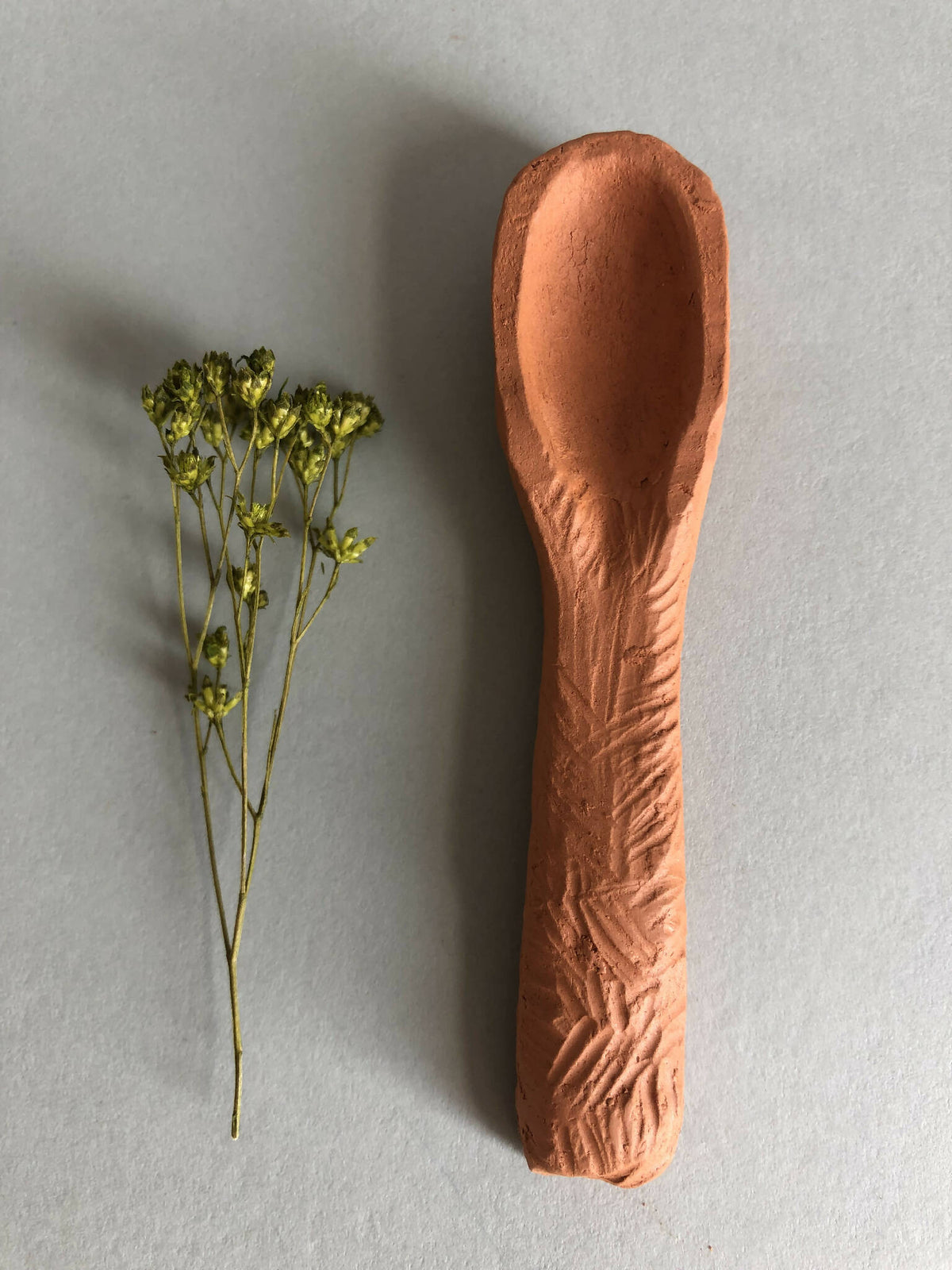 Cuillère à thé en brun cuivré, tête ovale et manche allongé.