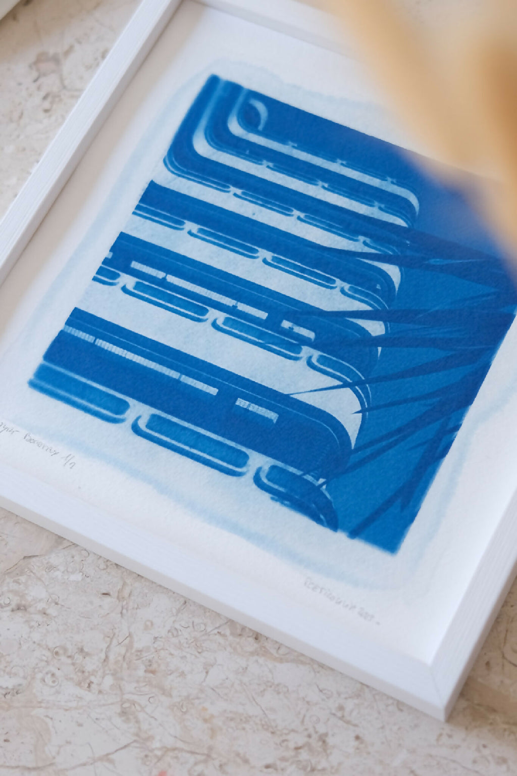 Tirage cyanotype bleu en cadre blanc, gros plan du motif abstrait géométrique.