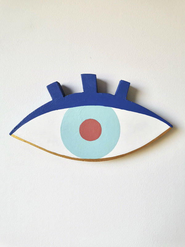 Œil en peinture sur bois, fond blanc, iris bleu clair et pupille orange.