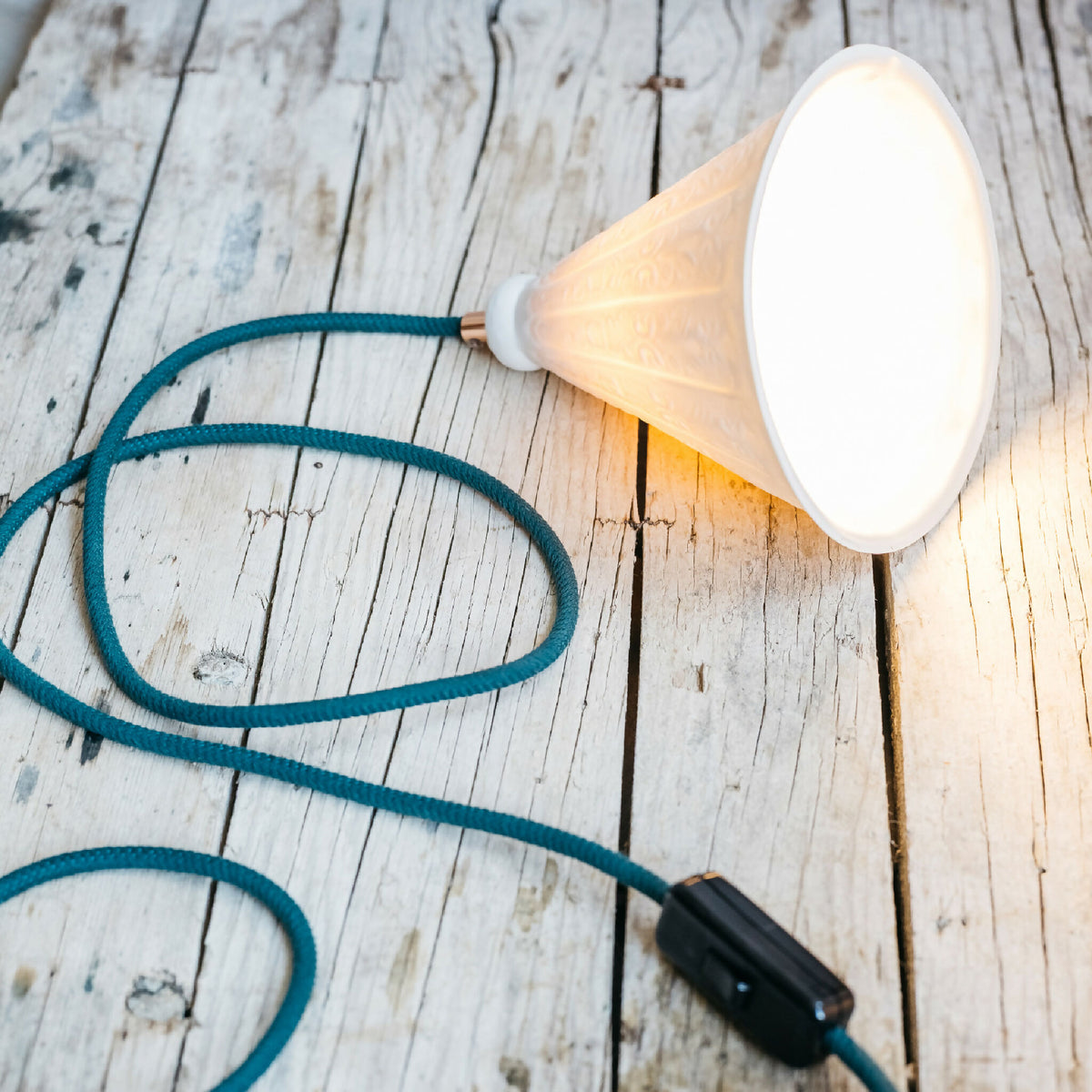 Lampe en porcelaine blanche avec abat-jour conique et câble bleu, prise noire