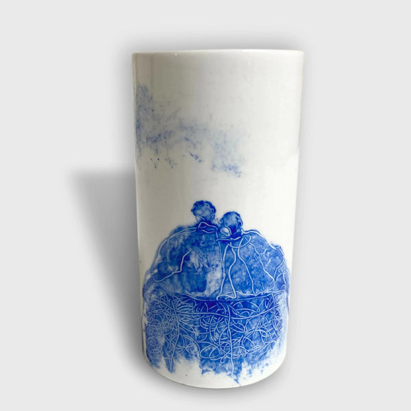 Vase en céramique blanc avec illustration bleue d’un couple méditant, motif au bas.