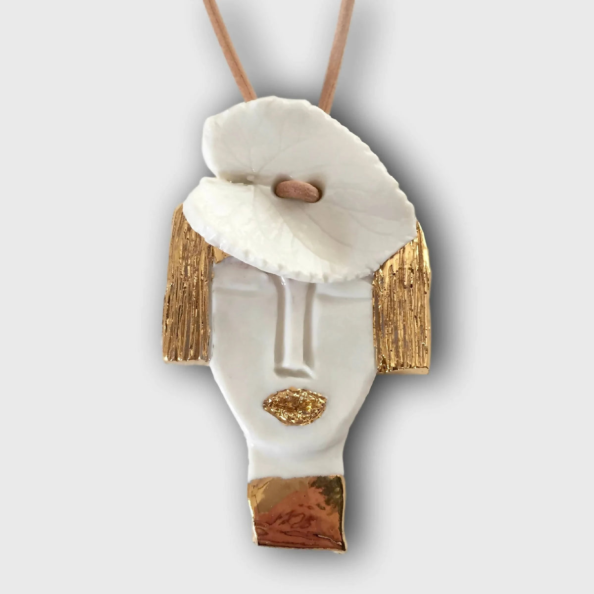 Pendentif en porcelaine blanche, finitions dorées et visage sculpté, cordon beige