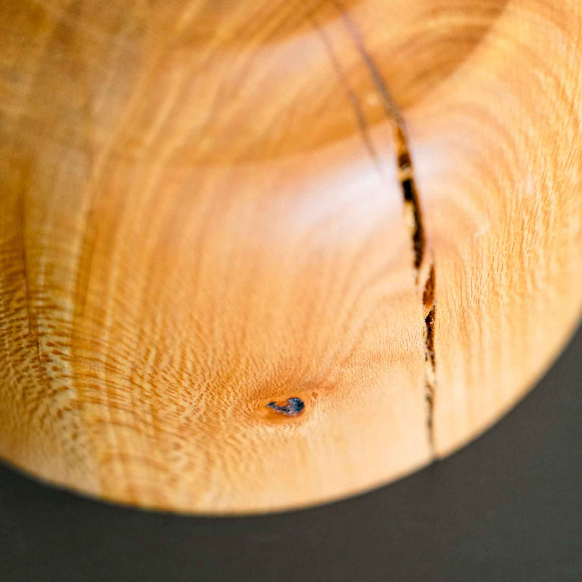 Bol en bois clair avec nœud bleuâtre et couture sombre sur le bord