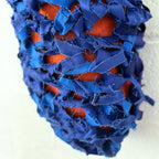 Cocoon décoratif bleu en tissu frangé, avec détails orange visibles