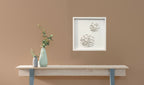 Petit tableau encadré en relief, motifs blancs, au-dessus d’une console