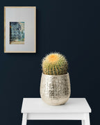 Tableau abstrait en cadre beige, motif bleu-vert, posé au-dessus d’une table blanche.