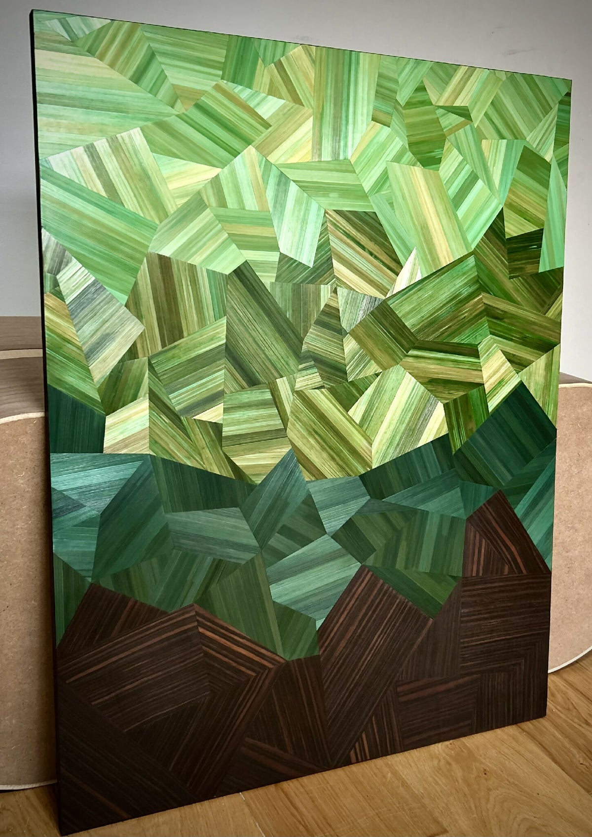 Tableau posé : motif en cubes verts et motifs facettés, base brun foncé, cadre noir.