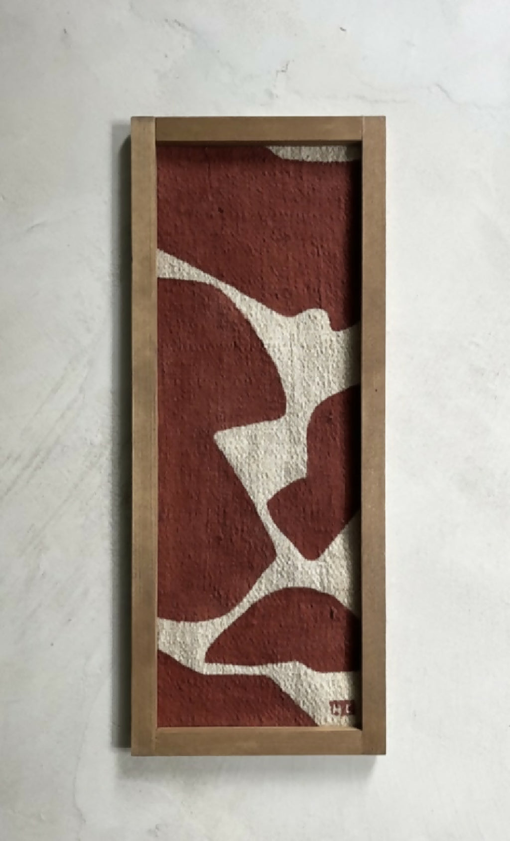 Tableau abstrait en cadre bois brun clair, formes beige sur fond bordeaux.
