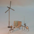 Sculpture en acier : mât à pales, livre ouvert et petits personnages sur socle.