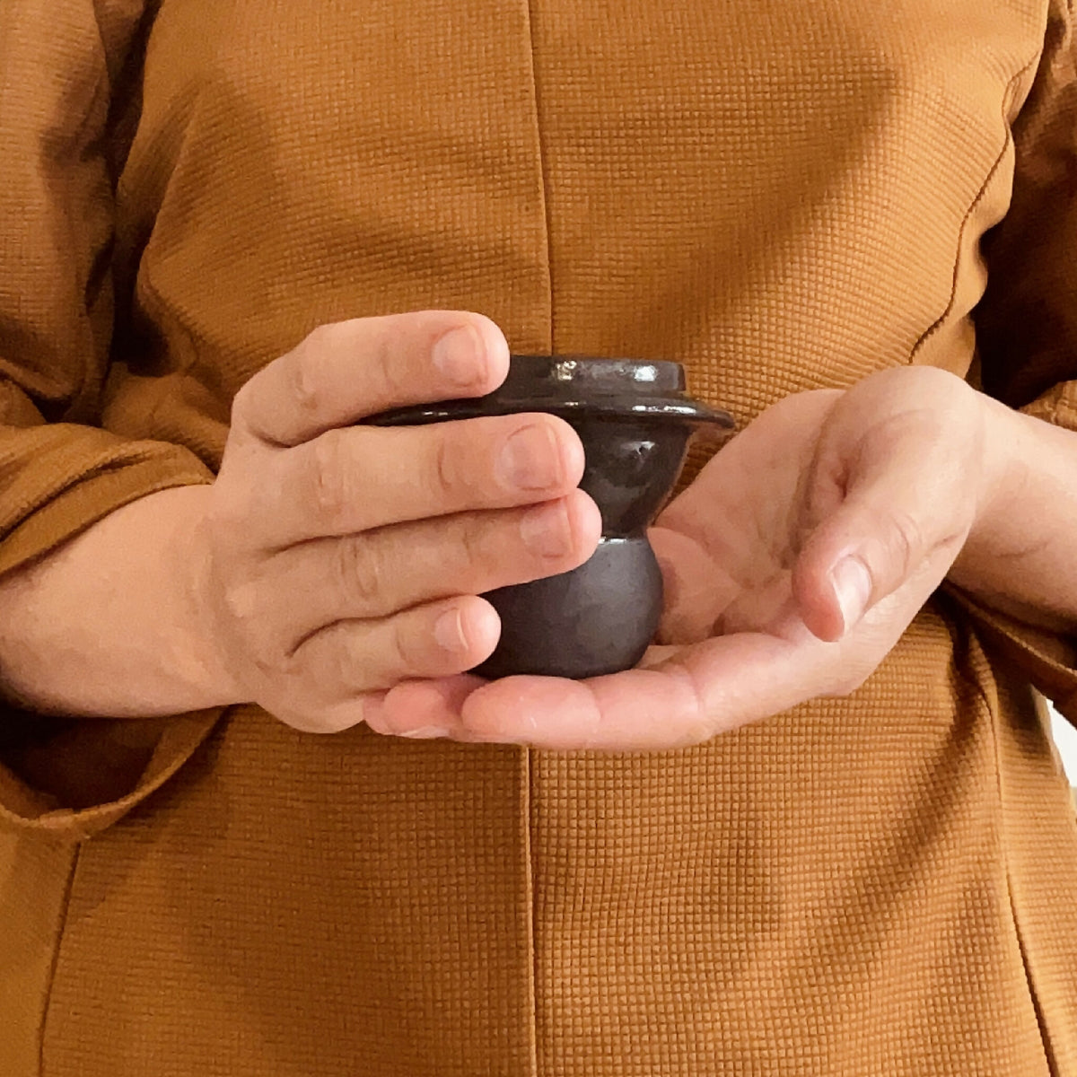 Duo de tasses à café en céramique sombre, tenu à deux mains