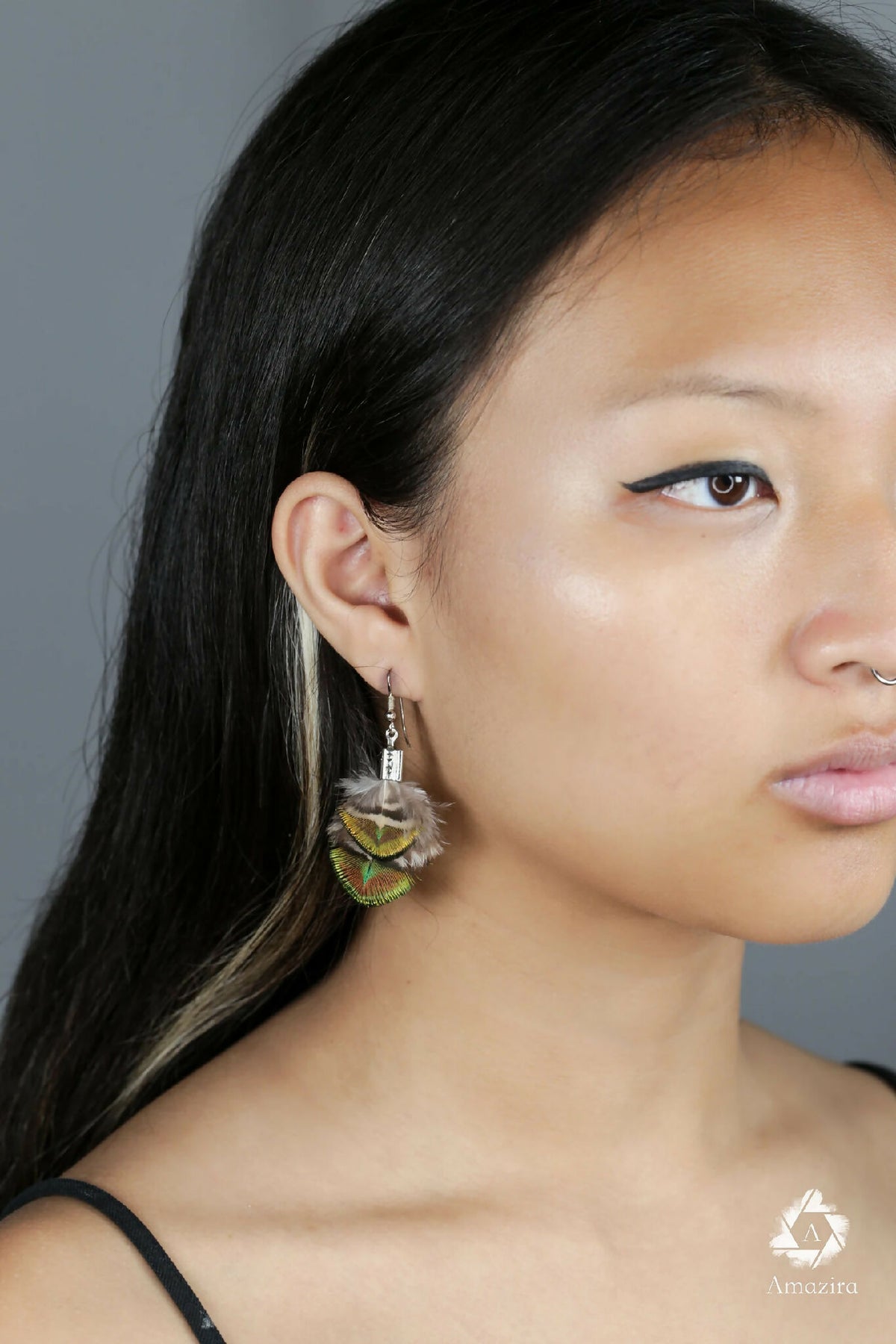 Boucles d’oreilles plumes de paon vertes et bleues, acier argenté, portées de profil.