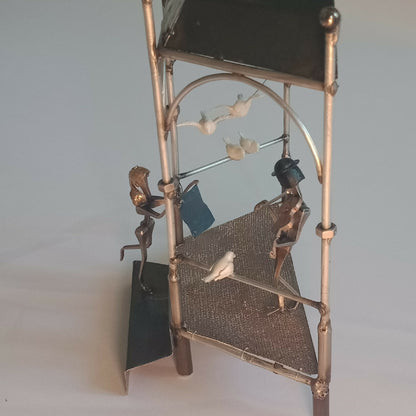 Manège décoratif avec figurines, barre arquée et oiseau en blanc en suspension.