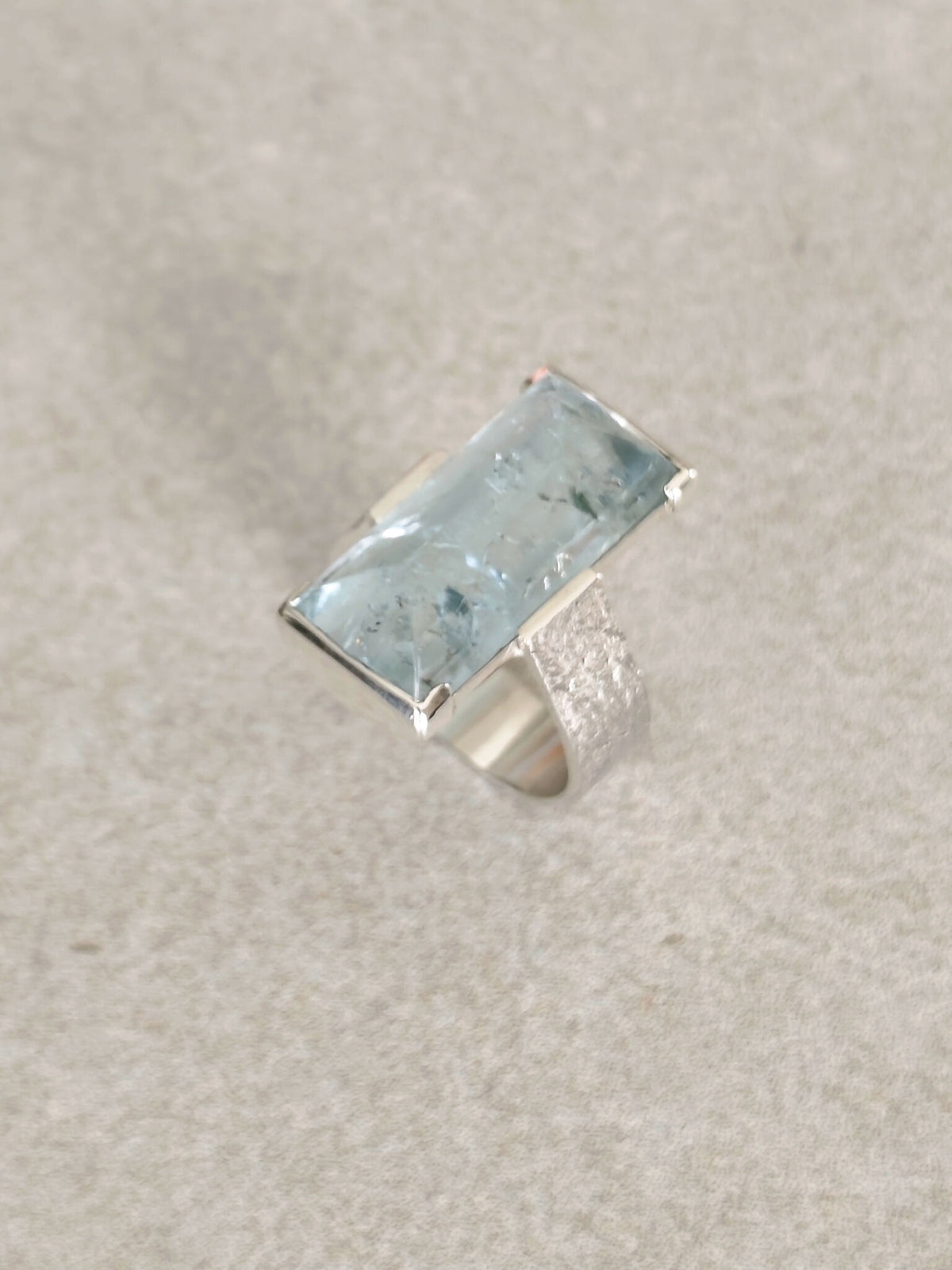 Bague en topaze bleu clair rectangulaire, monture argent, vue de profil.