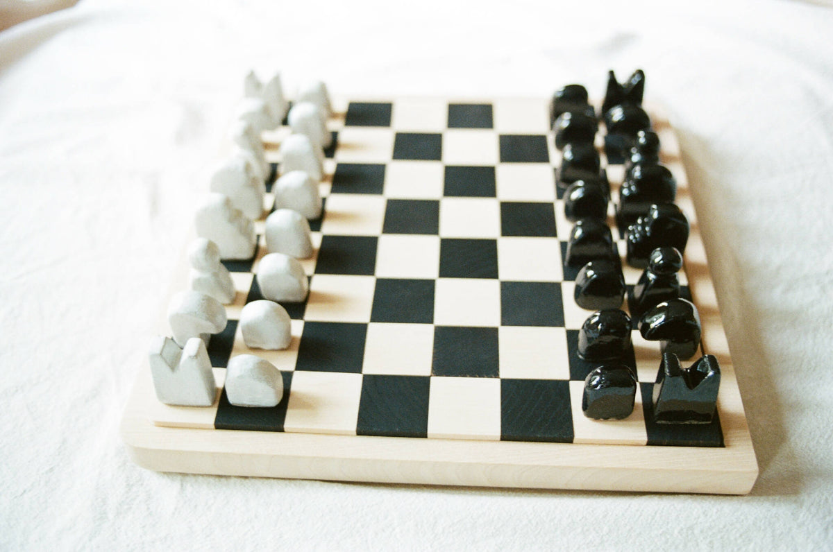 Échiquier en bois avec cases alternées noir et blanc, pièces en céramique blanc et noir