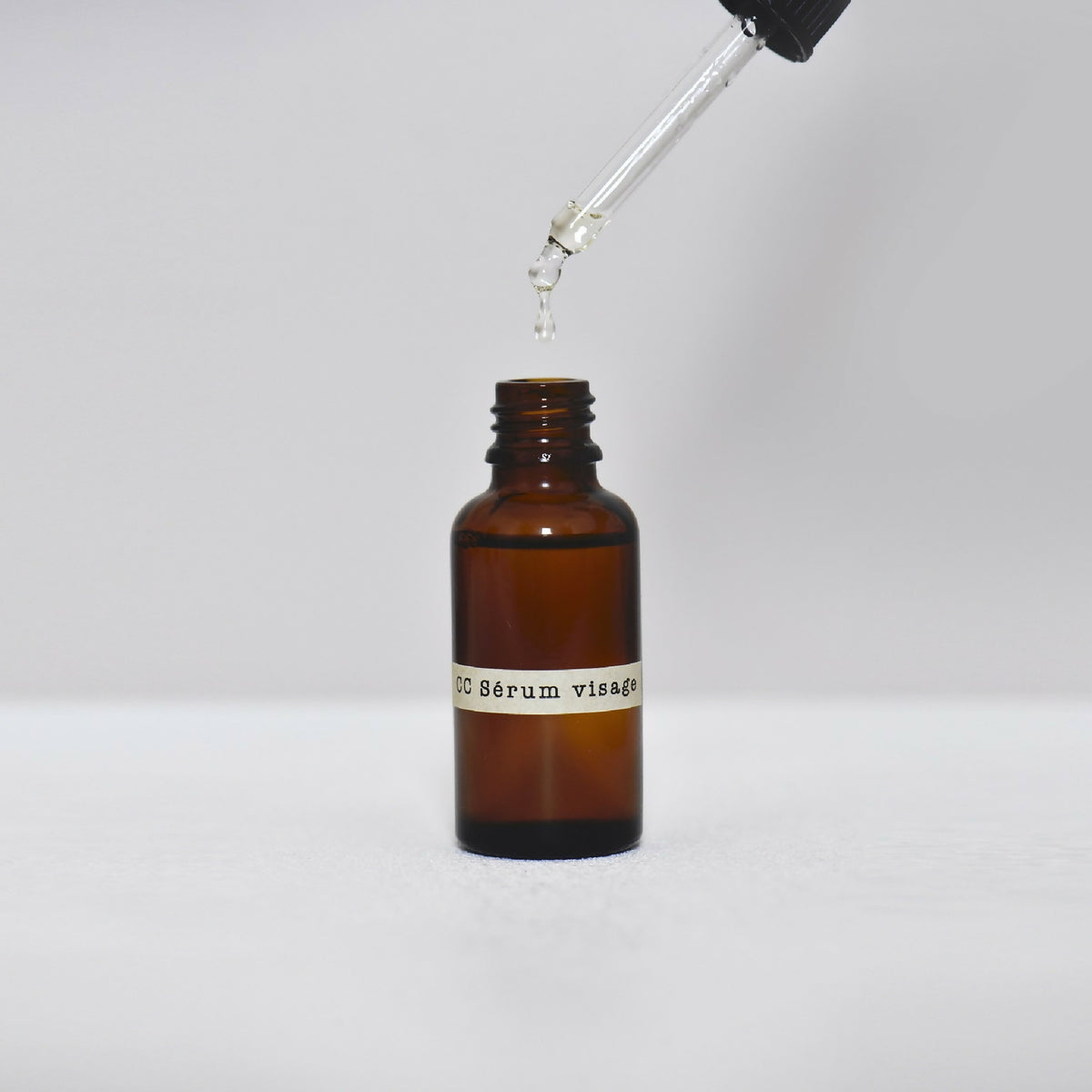 Flacon de sérum visage en verre ambré avec pipette déversant du liquide