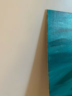Coin de toile abstraite bleu-vert sur mur, bord de toile et coups de pinceau.