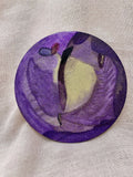 Badge rond en tissu violet avec motif cosmique, sur fond clair
